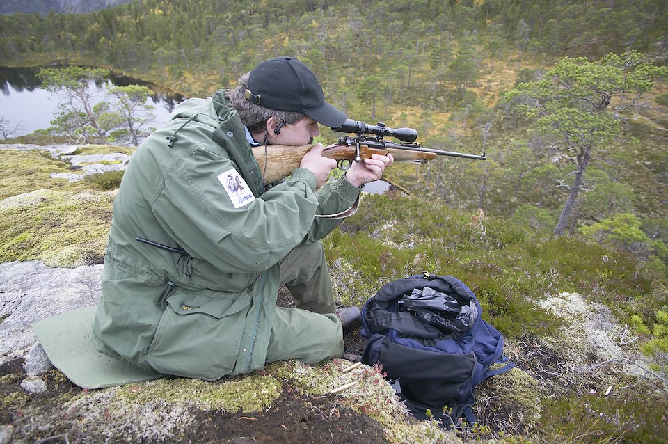 Berndt Dahle, Norwegian hunter sat atop cliff in forest awaiting elk (moose) to be driven by dogs, Nord-Trondelag, Norway